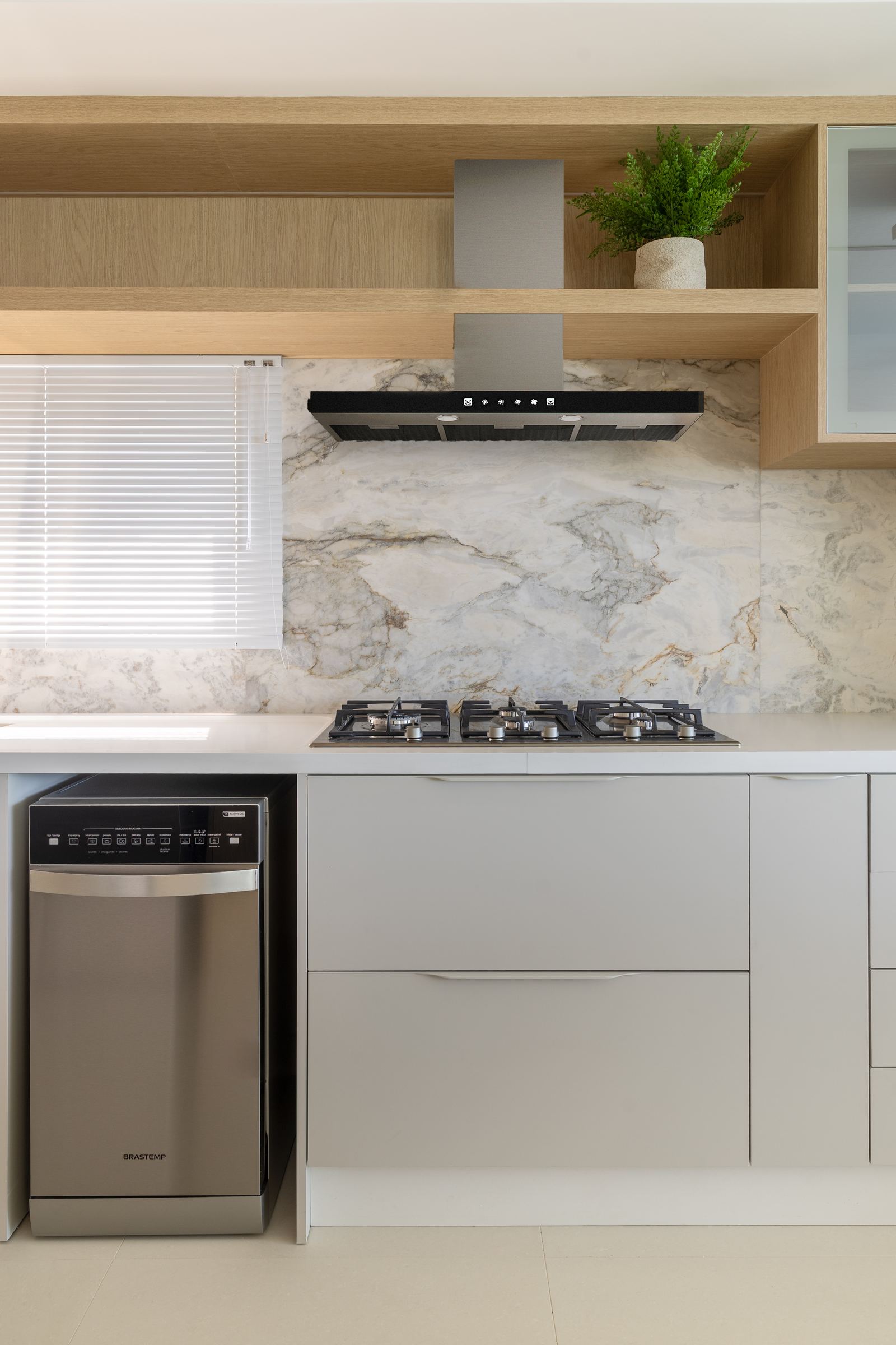Cooktop e coifa sobre bancada de quartzo, com frontão em mármore